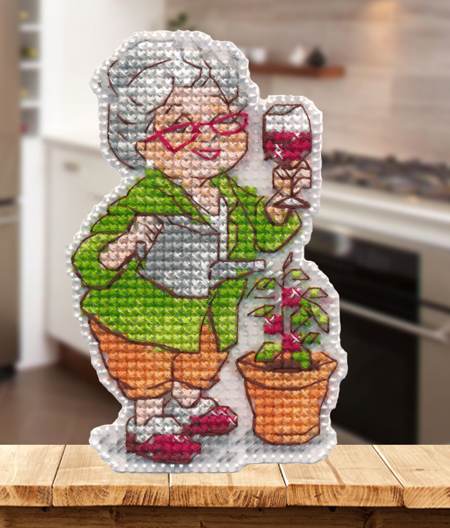 Kit de punto de cruz Oven S1729 Magnet Joy in the Little Things con señora mayor regando una planta, copa en la mano y diseño de imán sobre canvas plástico.