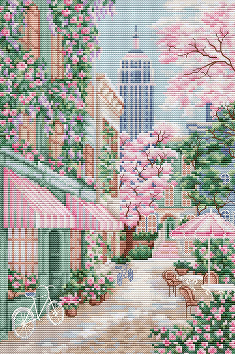 Calle de Nueva York con flores rosadas y cafetería bordada en punto de cruz estilo urbano primaveral